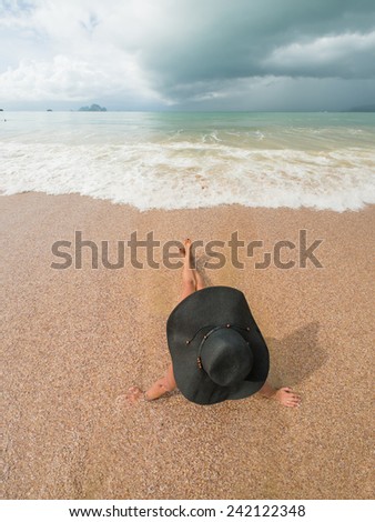 watching the coming sea storm - beautiful woman lying on the beach