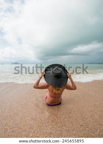 watching the coming sea storm - beautiful woman lying on the beach