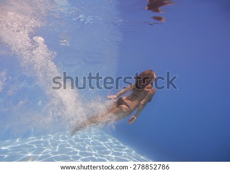 female swimmer after jumping with air bubbles trail in blue water