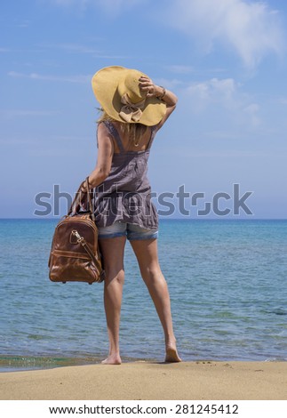 Woman with leather travel bag on the beach going on holidays