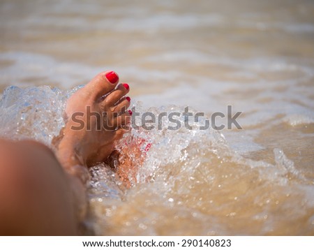 water splash on nice female legs on beach