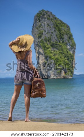 Woman with leather travel bag on the beach going on holidays