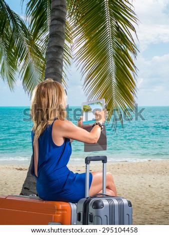 Woman with suitcases and tablet on the tropical beach