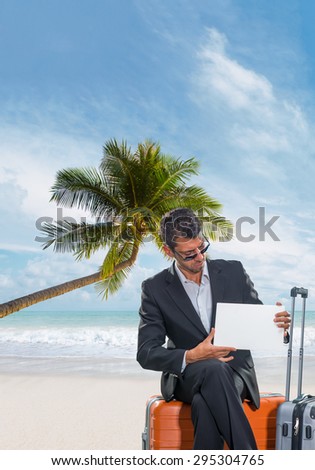 Man in suit sitting on his luggage at the tropical beach