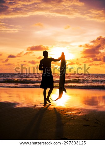 Surfer on the ocean beach at sunset on Bali island, Indonesia