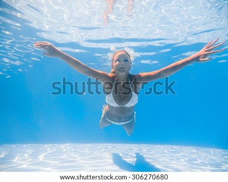 A young blonde woman diving in a blue clean water