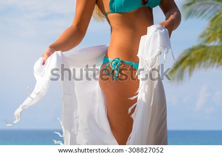 Body part of woman with perfect body on the beach, sexy slim model wearing swimwear and skirt, summer vacation concept