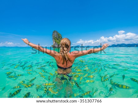 Woman swimming with snorkel surrounded by fish, Andaman Sea, Thailand