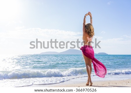Portrait of young woman wearing a pink sarong and bikini  on the tropical beach
