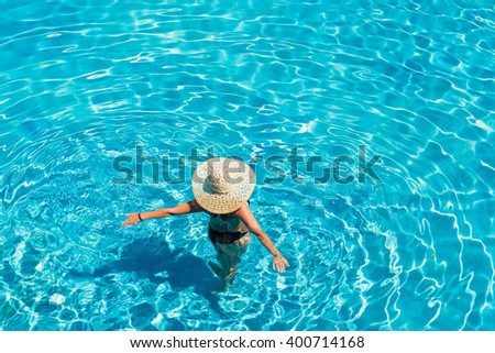 Young woman in bikini wearing a straw hat at the swimming pool