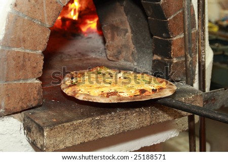 Gourmet Pizza coming out of wood fired Pizza Oven in restaurant