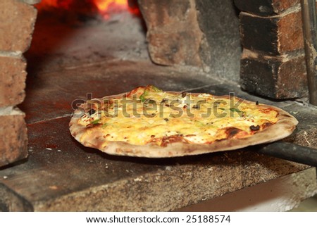 Gourmet Pizza coming out of wood fired Pizza Oven in restaurant