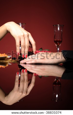 Close up of young couple at restaurant table with woman\'s hand resting on man\'s hand.