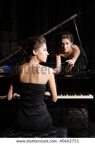 A beautiful young woman playing piano with her twin on the piano
