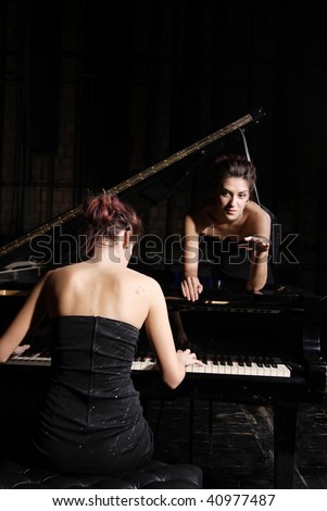 A beautiful young woman playing piano with her twin on the piano
