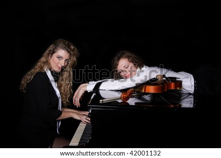 Two beautiful young sexy women posing with violin and piano