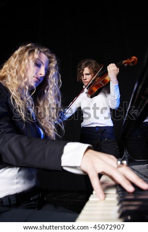 Two beautiful young sexy women posing with violin and piano