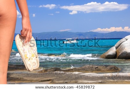 woman holding flip flops on the shoreline
