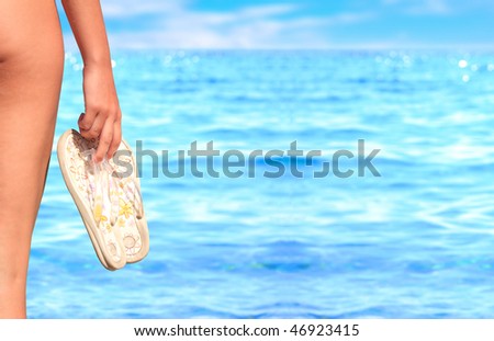 woman holding a pair of flip flops in the water