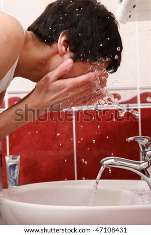 Young man washing face in the bathroom