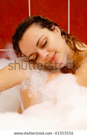 Young woman enjoys bath-foam in the bathtub.