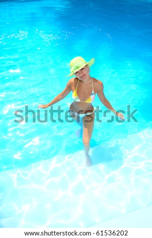 Beautiful young woman relaxing in a swimming pool in Greece