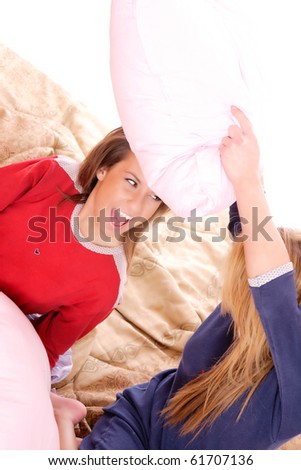 Two beautiful young woman fighting with pillows in bed