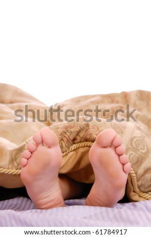 View of a couple\'s feet sticking out of the bed sheet while in bed