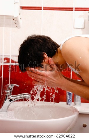 Young man washing face in the bathroom