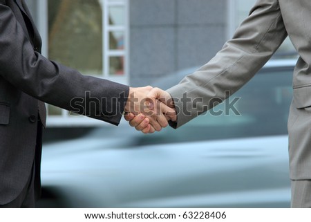 two Handsome  Businessman shaking hands in front of corporate