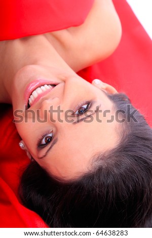 Portrait of a beautiful young woman under red satin sheet isolated over white background