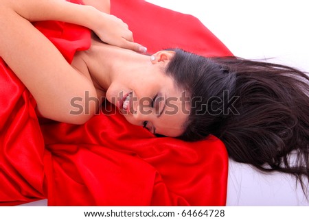 Portrait of a beautiful young woman under red satin sheet