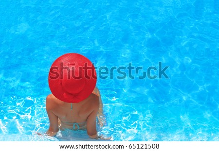 Pretty woman with red hat enjoying a swimming pool in Greece