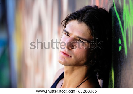 young handsome man in front of graffitti wall