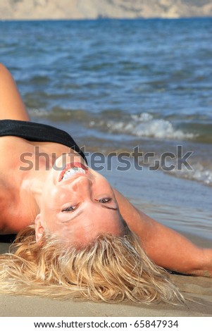 Young Woman Sunbathing On Beach in Greece