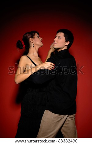 A beautiful young couple dancing salsa over red background