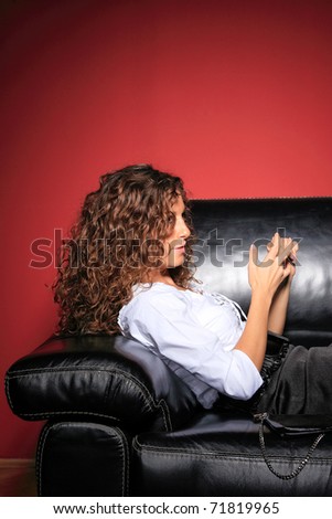 Young woman in black skirt and white dress sitting on black sofa