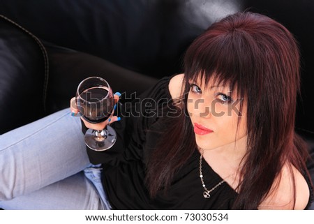 A young woman relaxes at home on the sofa with a glass of red wine