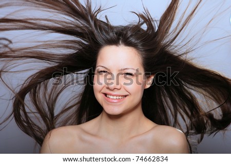 Portrait of glamour woman over gray background with flying hair