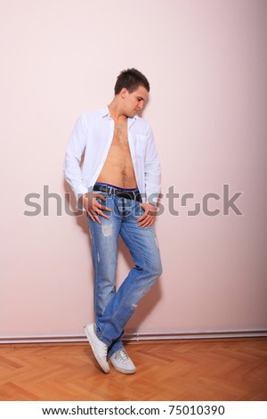 portrait of a young man with unbuttoned shirt over light pink wall