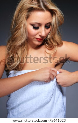 Young, healthy and beautiful woman in towel over gray background