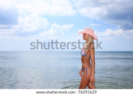 Sexy and fit blond woman wearing a pink hat  in the sea