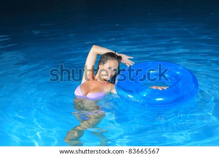 Attractive girl posing in swimming pool at night