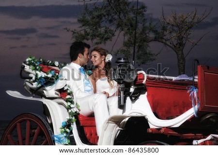Beach wedding: bride and groom on a carriage by the sea