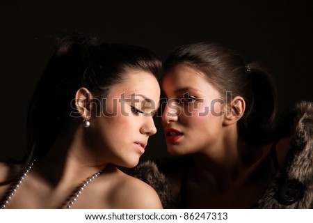Two sexy girls posing on dark background.