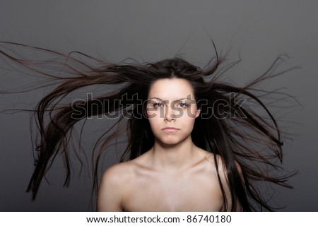 A beautiful glamorous woman in front of a black background with her hair blowing in the wind.