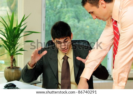 Two businessmen discussing tasks at office desk