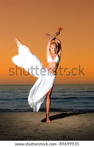 Beautiful young woman with hat metitating on the beach in Greece at sunset