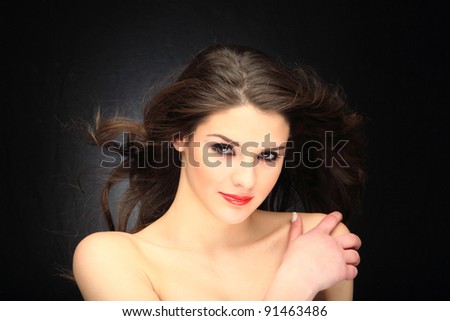 Glamour portrait of a woman on black with hair blowing with the wind