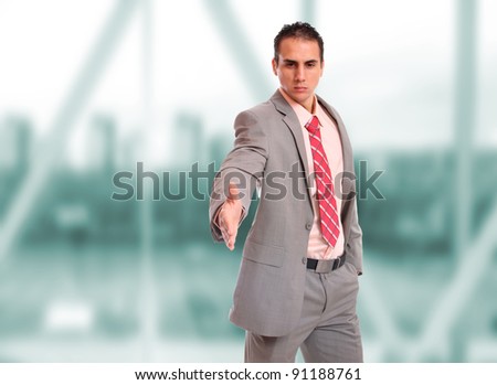 Closeup of a young business man thumb up standing in a light and modern business hall.